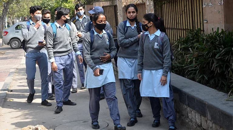 اسکول کے طلباء ماسک پہنے سڑک پر چل رہے ہیں۔