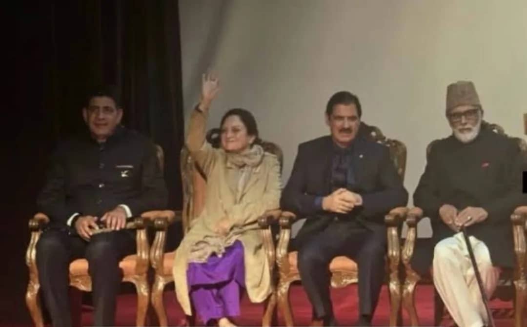 چار افراد کرسیوں پر بیٹھے ہیں، ایک عورت اپنا ہاتھ اٹھا رہی ہے۔