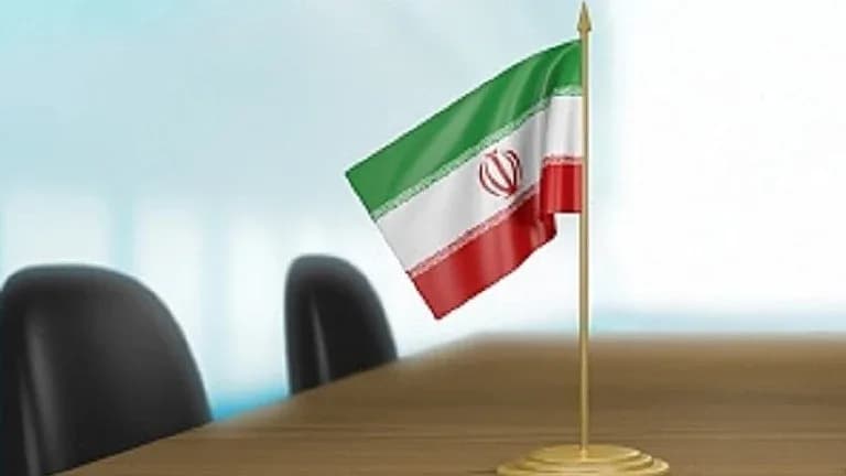 ایک میز پر ایران کا پرچم اور کرسیاں۔
