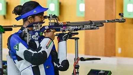 ایک خاتون شوٹر نیلے اور سفید رنگ کی وردی میں رائفل کے ساتھ نشانہ لگا رہی ہے۔
