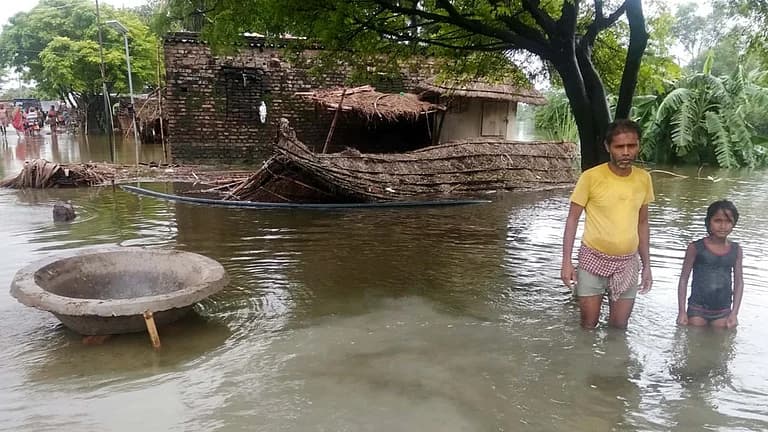 سیلاب زدہ علاقے میں ایک مرد اور ایک بچی پانی میں کھڑے ہیں۔